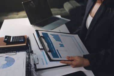 Modern ofiste işbirliği yapan denetçiler, finansal belgeleri analiz ediyorlar ve çizelgeleri gösteren bir dizüstü bilgisayarla hesap makinesi kullanıyorlar. Ticarette denetim ve vergiler