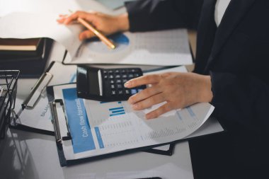 Modern ofiste işbirliği yapan denetçiler, finansal belgeleri analiz ediyorlar ve çizelgeleri gösteren bir dizüstü bilgisayarla hesap makinesi kullanıyorlar. Ticarette denetim ve vergiler