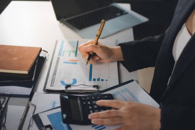 Modern ofiste işbirliği yapan denetçiler, finansal belgeleri analiz ediyorlar ve çizelgeleri gösteren bir dizüstü bilgisayarla hesap makinesi kullanıyorlar. Ticarette denetim ve vergiler