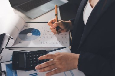 Modern ofiste işbirliği yapan denetçiler, finansal belgeleri analiz ediyorlar ve çizelgeleri gösteren bir dizüstü bilgisayarla hesap makinesi kullanıyorlar. Ticarette denetim ve vergiler