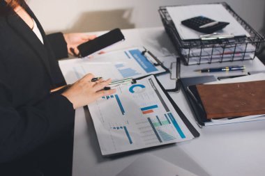 Modern ofiste işbirliği yapan denetçiler, finansal belgeleri analiz ediyorlar ve çizelgeleri gösteren bir dizüstü bilgisayarla hesap makinesi kullanıyorlar. Ticarette denetim ve vergiler