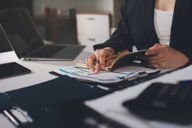 Modern ofiste işbirliği yapan denetçiler, finansal belgeleri analiz ediyorlar ve çizelgeleri gösteren bir dizüstü bilgisayarla hesap makinesi kullanıyorlar. Ticarette denetim ve vergiler