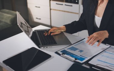 Modern ofiste işbirliği yapan denetçiler, finansal belgeleri analiz ediyorlar ve çizelgeleri gösteren bir dizüstü bilgisayarla hesap makinesi kullanıyorlar. Ticarette denetim ve vergiler