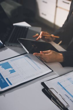 Modern ofiste işbirliği yapan denetçiler, finansal belgeleri analiz ediyorlar ve çizelgeleri gösteren bir dizüstü bilgisayarla hesap makinesi kullanıyorlar. Ticarette denetim ve vergiler