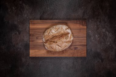 Dikdörtgen cevizli ahşap tahta üzerinde düz ekşi ceviz ekmeği, yerleşim için etrafında boş bir somun ile ortalanmış
