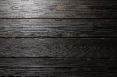 Yan ışıklandırmalı eskimiş ahşap masa arka plan ve tasarım için uygun yüksek kontrastlı dokular ve karamsar yüzey oluşturuyor.