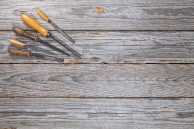 Ahşap saplı beş yıpranmış metal dosya yıpranmış ahşap tezgahın içini gösteriyor. Çerçevenin geri kalanı metin veya tasarım için bir sürü boş alan bırakır.