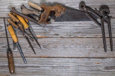 Makaslar, dosyalar, spatula, testere, tornavida, tente ve kerpeten de dahil olmak üzere klasik el aletleri yıpranmış çalışma tezgahının ortasına yerleştirilmiştir. Kalan alan metin ya da tasarım ögeleri eklemek için temizdir.