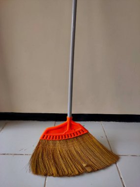 Döşeme ve diğer yüzeyleri temizlemek için kullanılan bir aleti işaret eden fayanslı zeminde duvara yaslanmış basit bir süpürge temizliği korumak için gerekli bir ev eşyası. 