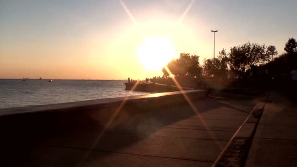 People walking at the seaside in sunset — Stock Video