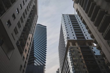 Gökdelenler bulutlu gökyüzünün altında dar bir caddenin üzerinde kule gibi. Yüksek kalite fotoğraf