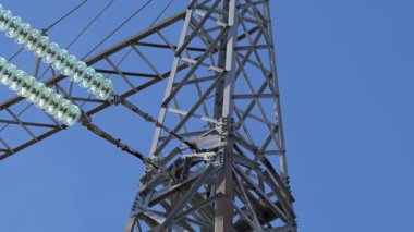 Açık gökyüzüne sahip bir güç iletim kulesinin yakın görüntüsü.