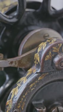 Siyah dikiş makinesinin üzerinde dönen metal bir el tekerleğinin dikey yakın çekimi