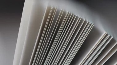 Bir kitapta, dokuyu ve ritmik hareketi gösteren beyaz kağıt sayfalarının aşırı yakın plan görüntüsü