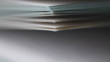 Bir kitapta, dokuyu ve ritmik hareketi gösteren beyaz kağıt sayfalarının aşırı yakın plan görüntüsü