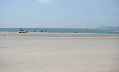 Batı Wittering, Batı Sussex, İngiltere. 17 Haziran 2025. Güneşli bir günde sığ Turkuaz Suyu, Cankurtaran Aracı ve Uzak Burun Manzaralı Engin Sandy West Wittering Plajı