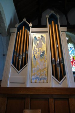 Batı Wittering, Batı Sussex, İngiltere. 17 Haziran 2025. St. Peter ve St. Paul Kilisesi, Batı Wittering 'deki' Melekler Bize Yardım Eder 'duvar resmiyle Yaldızlı Boru Organı Cephesi' ne yakın plan