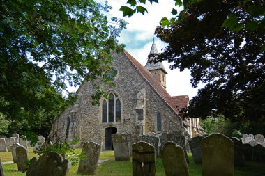 Warblington, Hampshire, İngiltere. 29 Haziran 2025. Warblington 'daki Ağaçlar Tarafından Çerçevelenen Aziz Thomas Becket Kilisesi ve Mezar Taşları