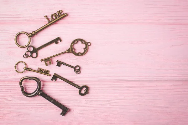 Kolekcja starych kluczy. Key Love i klucz Dream na różowym drewnianym tle. Przestrzeń kopiowania — Zdjęcie stockowe