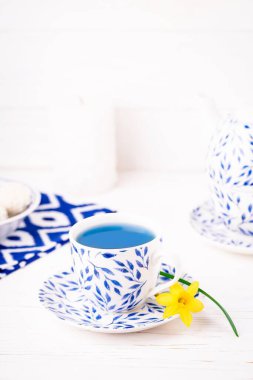 İçinde organik mavi çay ve küçük nergis çiçekleri olan bir fincan.