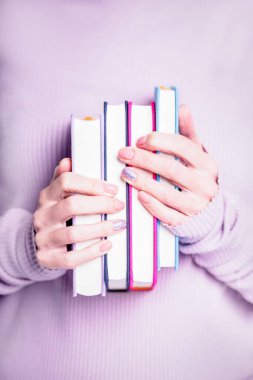 Hands holding four books on the violet background clipart
