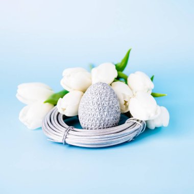 Yuvada gümüş Paskalya yumurtası ve beyaz laleler