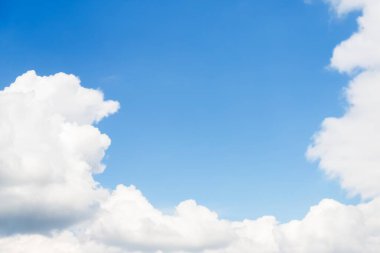 White large fluffy clouds frame a clear light blue sky