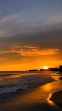 Hafif Dalgaların Yansıttığı Tropikal Plajda Altın Gün Batımı.