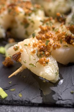 Geleneksel Bask morina şiş sarımsak ve zeytin yağı ile koyu bir tahta zemin üzerinde servis edilir.