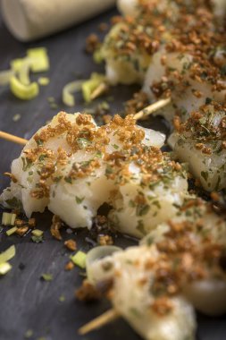 Geleneksel Bask morina şiş sarımsak ve zeytin yağı ile koyu bir tahta zemin üzerinde servis edilir.