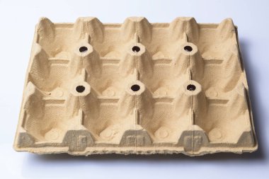 Beyaz arka planda boş bir karton yumurta kutusu. Yokluğu, boşluğu, ambalajı, sürdürülebilirliği, geri dönüşümü veya gıda tedarik sorunlarını temsil eden kavramsal görüntü