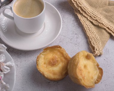 Geleneksel Bilbao pirinç kekleri açık gri desenli yüzeyde sıcak bir fincan kahveyle servis edilir.