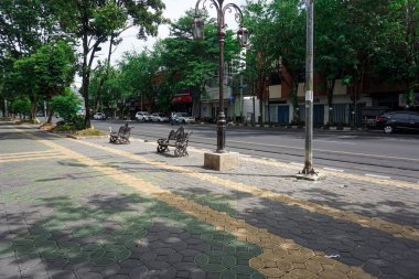 Yaz aylarında boş banklar ve yemyeşil ağaçlarla Sessiz Şehir Kaldırımı