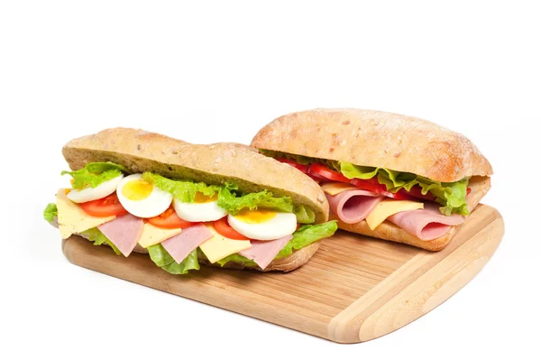 Два бутерброди на обробній дошці на білому тлі — стокове фото