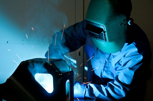 Welder working with electrode at semi-automatic arc welding.