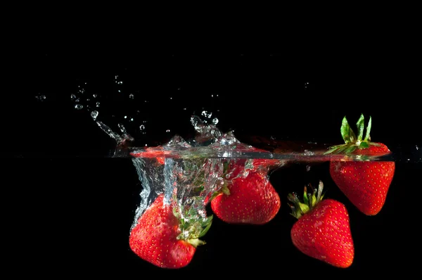 Strawberries splashing into water — Stock Photo, Image