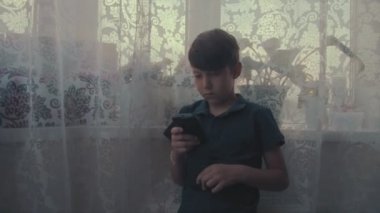 Üzgün çocuk yaptığı telefon pencerenin yakınındaki oyun oynamak