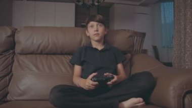 Konsol video oyunları oynarken çocuk evde kanepede