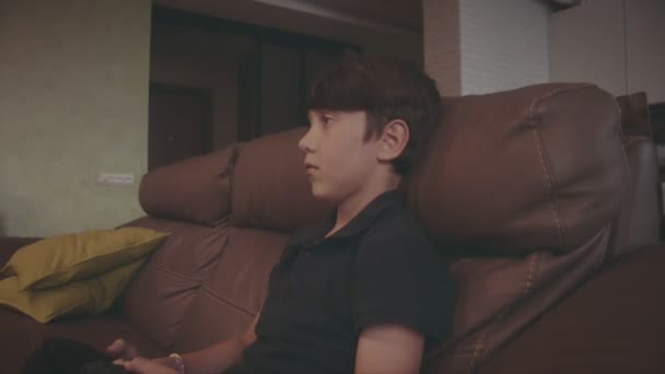 Chico jugando videojuegos en la consola en el sofá en casa — Vídeo de stock