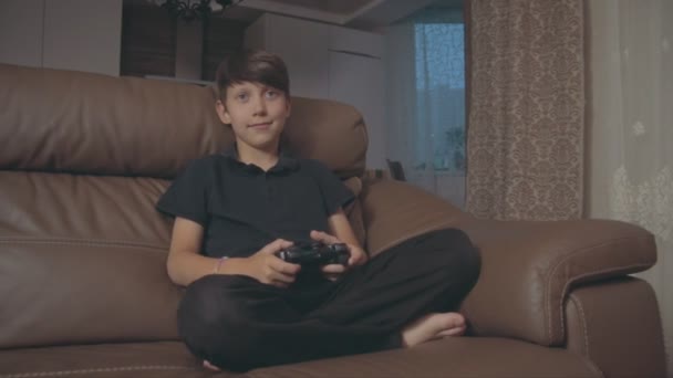 Anak laki-laki bermain video game di konsol di sofa di rumah — Stok Video