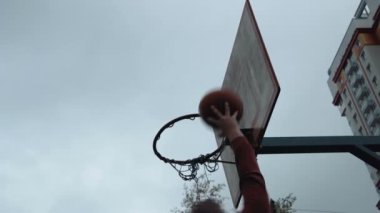 Genç adam açık havada sahada basket oynarken