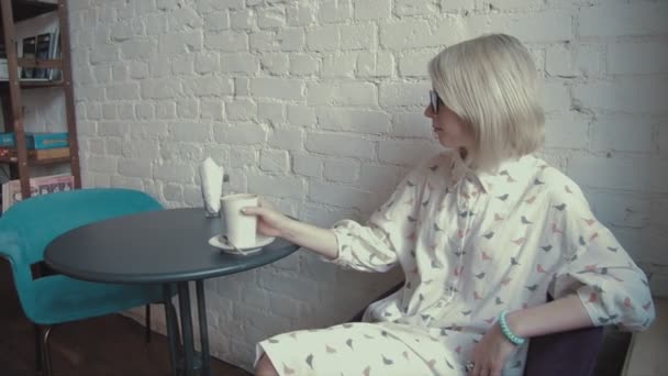 Gelukkig jonge mooie vrouw, drinken koffie in het café — Stockvideo