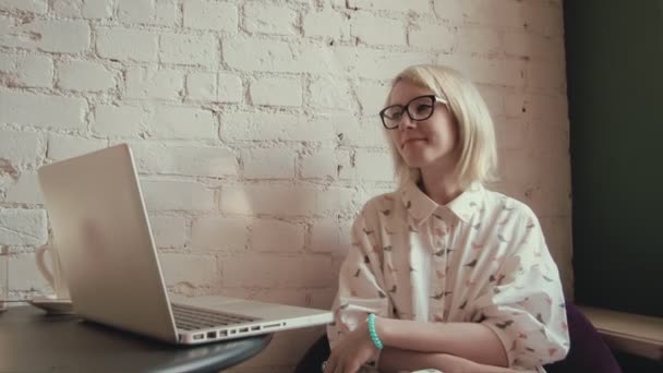 Glückliche junge schöne Frau, die im Café an ihrem Laptop arbeitet — Stockvideo