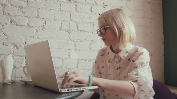 Glückliche junge schöne Frau, die im Café an ihrem Laptop arbeitet — Stockvideo