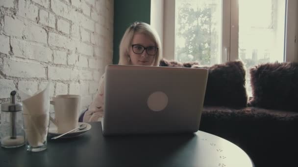 快乐年轻美丽的女人她在咖啡馆的笔记本电脑上工作 — 图库视频影像