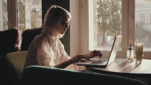 Happy young beautiful woman working on her laptop in the cafe — Stock Video