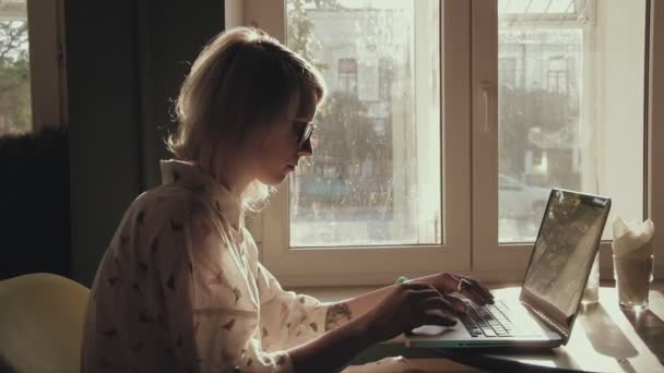 Щаслива молода красива жінка працює на ноутбуці в кафе — стокове відео