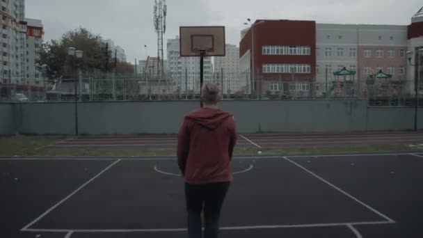 Joven jugando baloncesto al aire libre en la cancha — Vídeo de stock