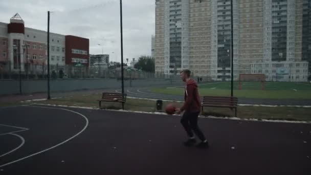 Ung man spelar basket utomhus på domstolen — Stockvideo