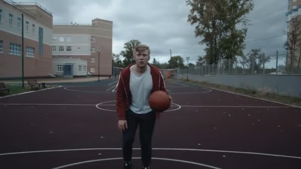 Mladý muž hraje basketbal venku na hřišti — Stock video